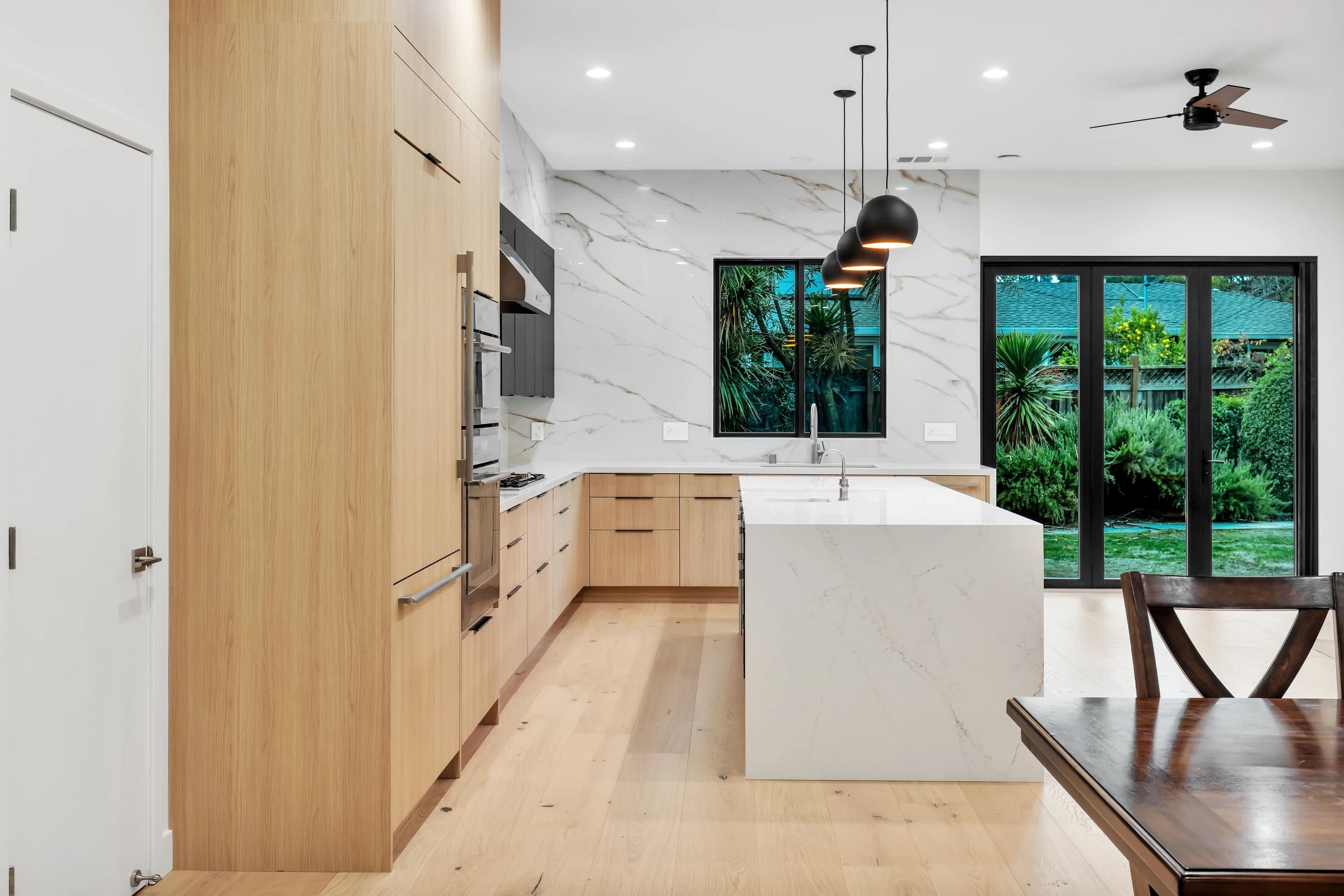 Los Altos modern kitchen remodel — dark waterfall island, wood cabinets, custom range hood by Inspired Builders