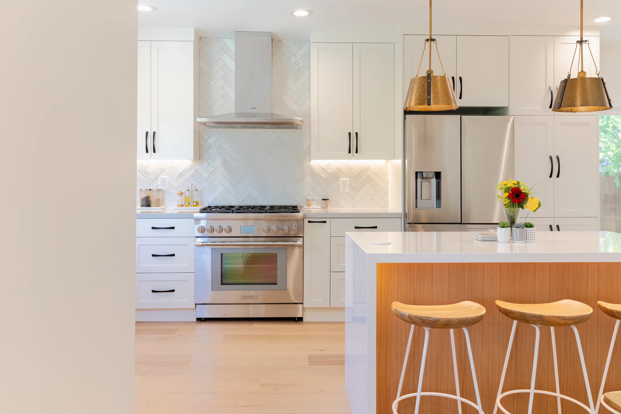 Foster City kitchen after remodeling with a warm wood island, white cabinetry, bar seating, and an open layout